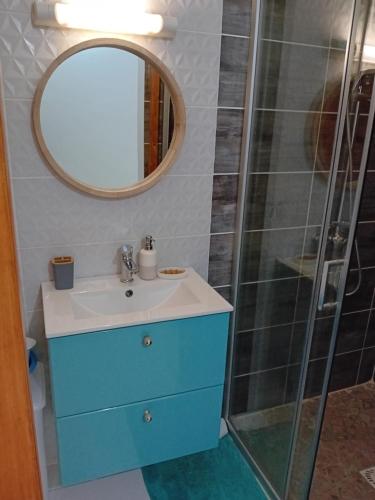een badkamer met een wastafel en een douche met een spiegel bij Maison dans les hauteurs in Le Gosier
