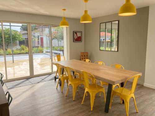 comedor con mesa de madera y sillas amarillas en Chai Nous, en Rion-des-Landes