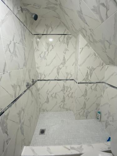 ein Bad mit einer Dusche und weißen Marmorfliesen in der Unterkunft Cheerful New Renovated One Private Bedroom in Morris Park
