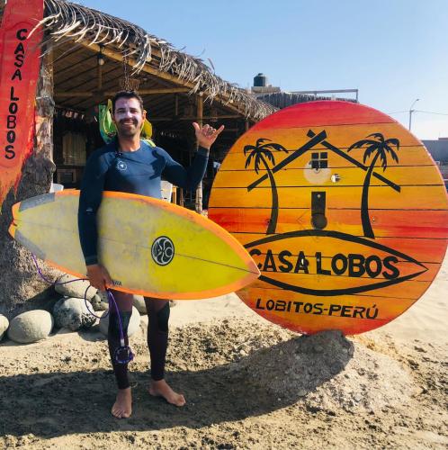a man standing on the beach holding two surfboards at Casa Lobos in Lobitos