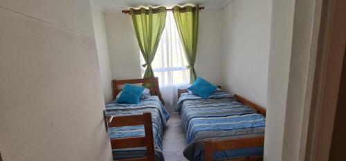 two twin beds in a room with a window at Arica verano y surf Dpto completo 2 habitaciones in Arica