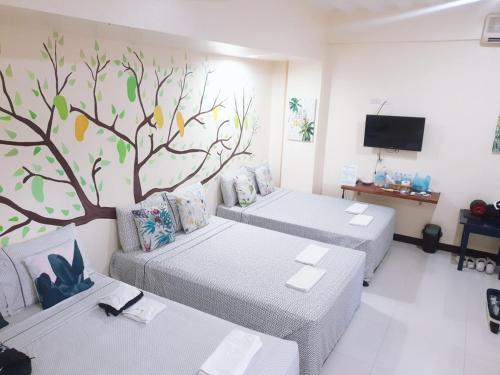 a room with two beds and a tree mural on the wall at Harang Hotel Mactan Lapulapu City Cebu Philippines in Maribago