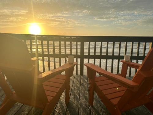 two chairs sitting on a balcony with the sun setting at Surfside Beachfront Dream in Surfside Beach