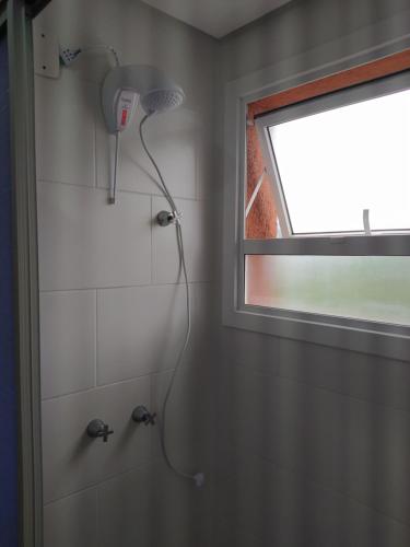 uma casa de banho com uma janela e um chuveiro com uma cabeça de chuveiro. em Apartamento próximo a gramado, 25km! em Três Coroas