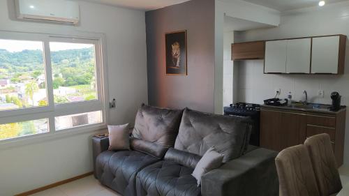 uma sala de estar com um sofá e uma cozinha em Apartamento próximo a gramado, 25km! em Três Coroas