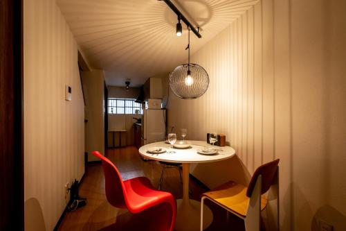 una sala da pranzo con tavolo bianco e sedie rosse di Healing Inn Osaka Fukushima ad Osaka