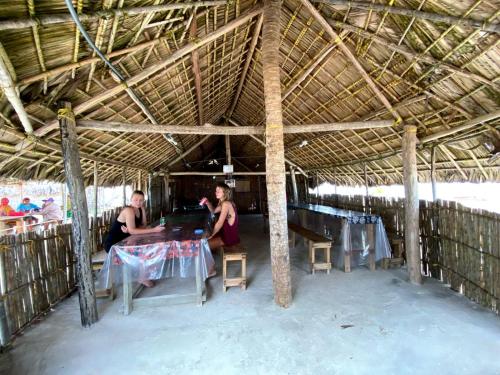 un grupo de personas sentadas en mesas en una cabaña de paja en Gunayar amazing en Arritupo Número Dos