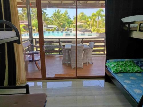 a room with a balcony with a table and a pool at Villa Royal Palawan in Narra