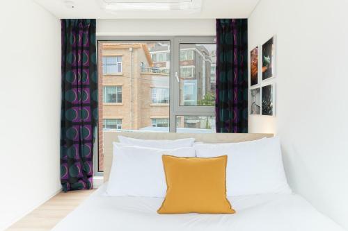 Un dormitorio con una cama blanca y una ventana. en La Loge, en Seúl