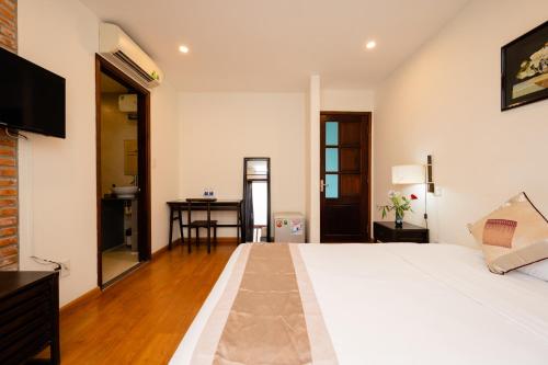 a bedroom with a large white bed and a desk at B'Lan Riverside Villa in Hoi An