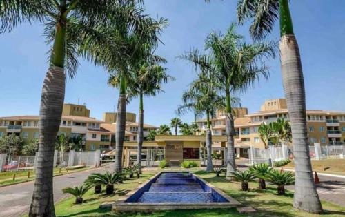 un complejo con piscina y palmeras en The Sun Resort - Super Apartamento de 2 quartos - 1 suíte e 1 reversível en Brasilia