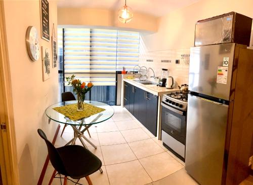 a kitchen with a table and a stainless steel refrigerator at Cusco Magico 7 - Minidepartamento Las Torres Kayser in Cusco