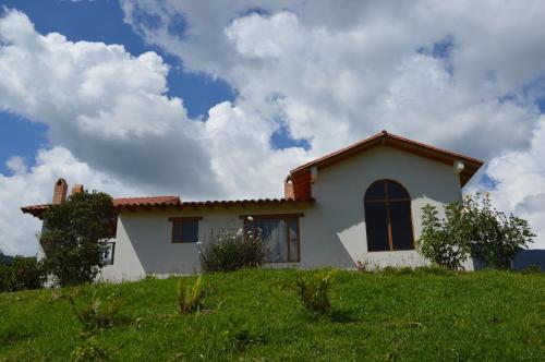 a white house on top of a grassy hill at Hacienda la Aurora Finca agroturística in Sotaquirá