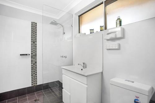 a white bathroom with a sink and a toilet at Lake Macquarie Motor Inn in Belmont