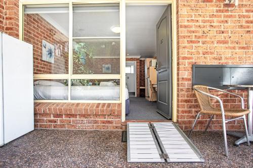 a room with a bed and a window and a desk at Lake Macquarie Motor Inn in Belmont