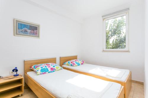 two beds in a room with a window at Apartments by the sea Zivogosce - Porat, Makarska - 20207 in Igrane