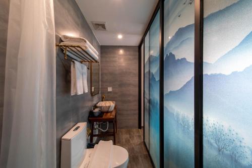 a bathroom with a toilet and a mural of mountains at Guipu Beihai Courtyard Hotel in Beijing