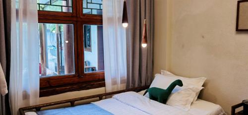 a green dinosaur sitting on a bed next to a window at Guipu Beihai Courtyard Hotel Beijing in Beijing