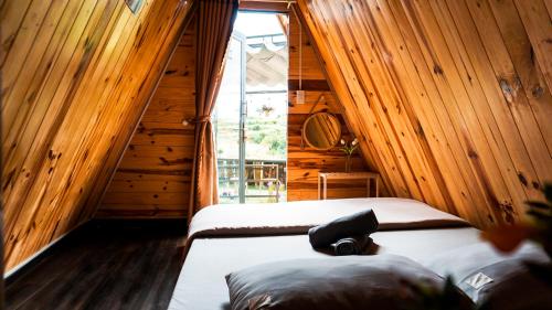 Ce lit se trouve dans un dortoir doté de murs en bois et d'une fenêtre. dans l'établissement Dalat 1AM, à Xuan An