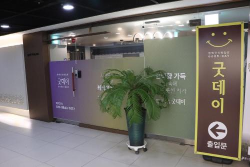 une plante en pot dans un hall avec un panneau dans l'établissement GoodDay Jjimjilbang, à Incheon