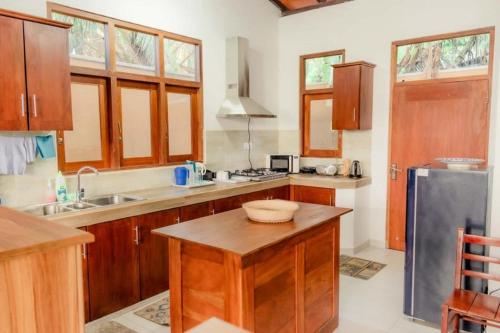 La cuisine est équipée d'armoires en bois et d'un réfrigérateur en acier inoxydable. dans l'établissement SaDev Lake Villa Bandaragama, à Bandaragama