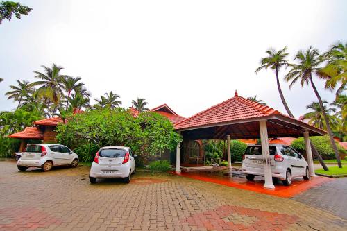 dos autos estacionados en un estacionamiento frente a una casa en SREE GOKULAM NALANDA RESORTS, en Nīleshwar