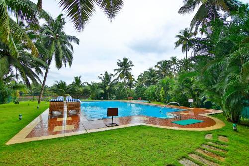 a swimming pool in a park with palm trees at SREE GOKULAM NALANDA RESORTS in Nīleshwar