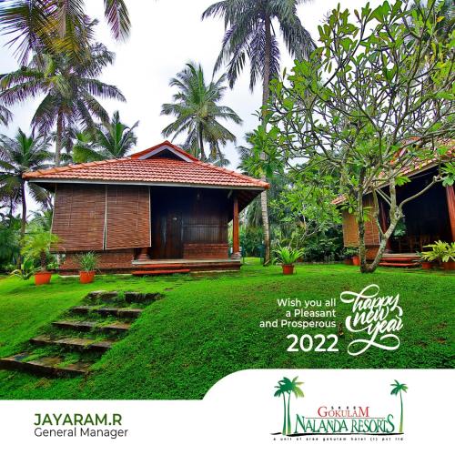 una pequeña casa en un patio verde con palmeras en SREE GOKULAM NALANDA RESORTS, en Nīleshwar