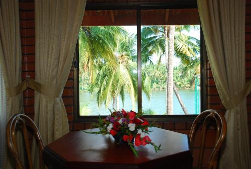 una mesa con flores delante de una ventana en SREE GOKULAM NALANDA RESORTS, en Nīleshwar