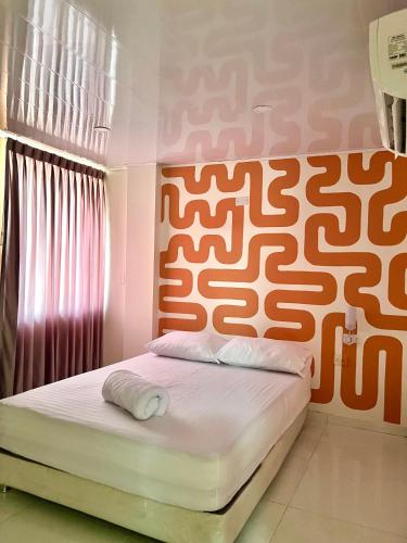 a bedroom with a bed with an orange and white headboard at Hotel Paranawa in Baranoa