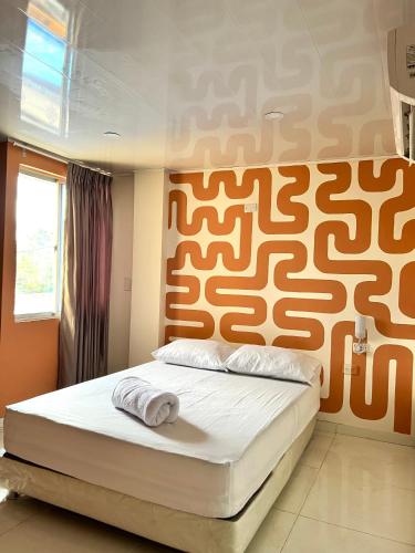 1 dormitorio con 1 cama con pared de color naranja en Hotel Paranawa, en Baranoa