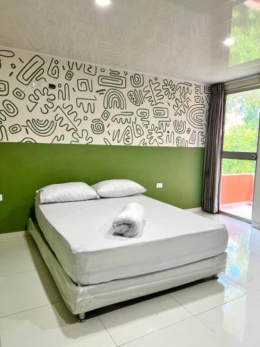 a bedroom with a large white bed with a wall with graffiti at Hotel Paranawa in Baranoa