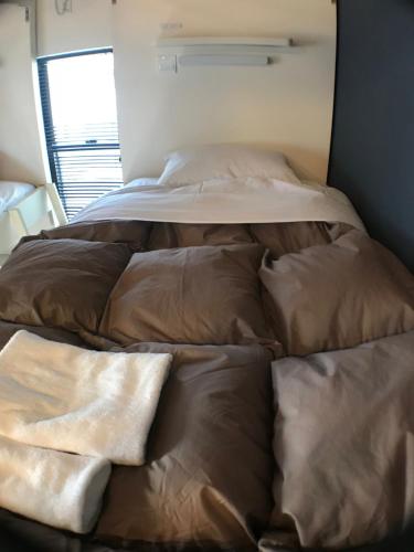 a bed with brown sheets and pillows in a room at LN13 貸切ゲストハウス三宮えびすや-Guest House Ebisuya- in Kobe