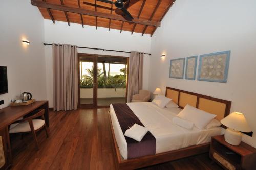 a bedroom with a bed and a desk and a television at Tantalize Beach in Hikkaduwa