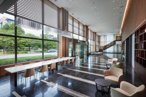 a lobby with a long table and chairs and windows at Hotel Interciti in Daejeon
