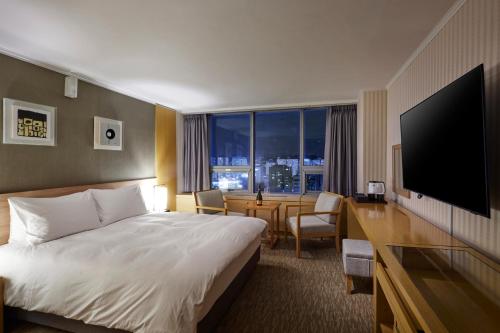 a hotel room with a bed and a desk with a television at Hotel Interciti in Daejeon