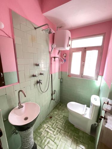 uma casa de banho rosa com um lavatório e um WC em Andrew Home em Catmandu
