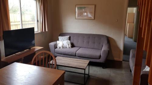 a living room with a couch and a tv at Billungar Unit 2 at Hat Head - 21 Creek Street in Hat Head