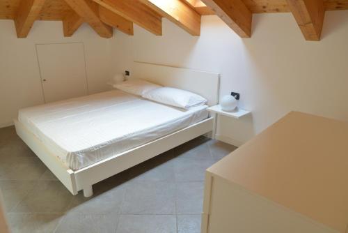 a white bedroom with a bed and a table at Cece' Dependance in Lecco