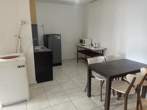 a kitchen with a table and chairs and a refrigerator at Globallon Services Apartment, Melaka Town Hotel in Malacca