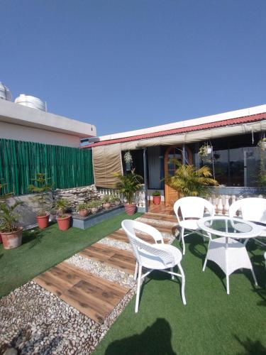 a patio with white chairs and a table on the grass at Ivy cottage Crown in Dehradun