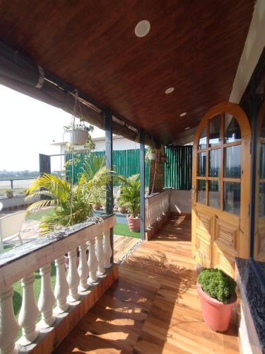 a porch with potted plants and a wooden railing at Ivy cottage Crown in Dehradun