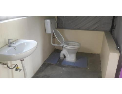 a bathroom with a toilet and a sink at Mussoorie Camp Resort in Mussoorie