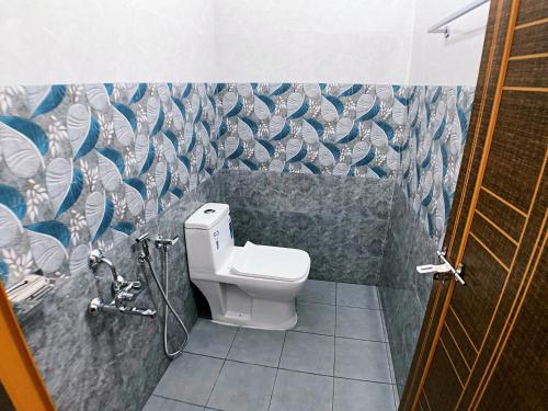 a bathroom with a toilet and a mosaic wall at Moon Wings Mountain Resort in Kanthalloor