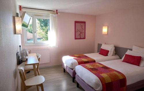 una camera d'albergo con due letti e una finestra di LOGIS Hôtel Le Moulin Des Gardelles a Riom