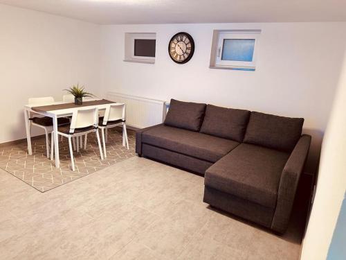 ein Wohnzimmer mit einem Sofa, einem Tisch und einer Uhr in der Unterkunft Gemütliche Wohnung in Leverkusen in Leverkusen