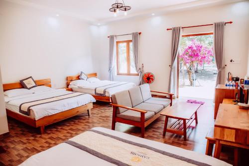 a room with two beds and a chair and a table at Cam Binh Resort Lagi in La Gi