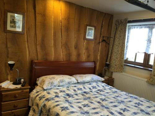 a bedroom with a bed and a wooden wall at Hoots End in Wool