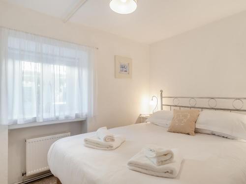 a bedroom with a white bed with towels on it at Dairy Cottage-uk45593 in Verwick