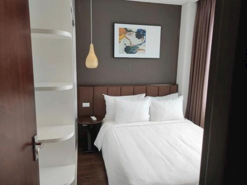 - une chambre dotée d'un lit avec des draps blancs et une photo dans l'établissement LaLaHome, à Bắc Ninh